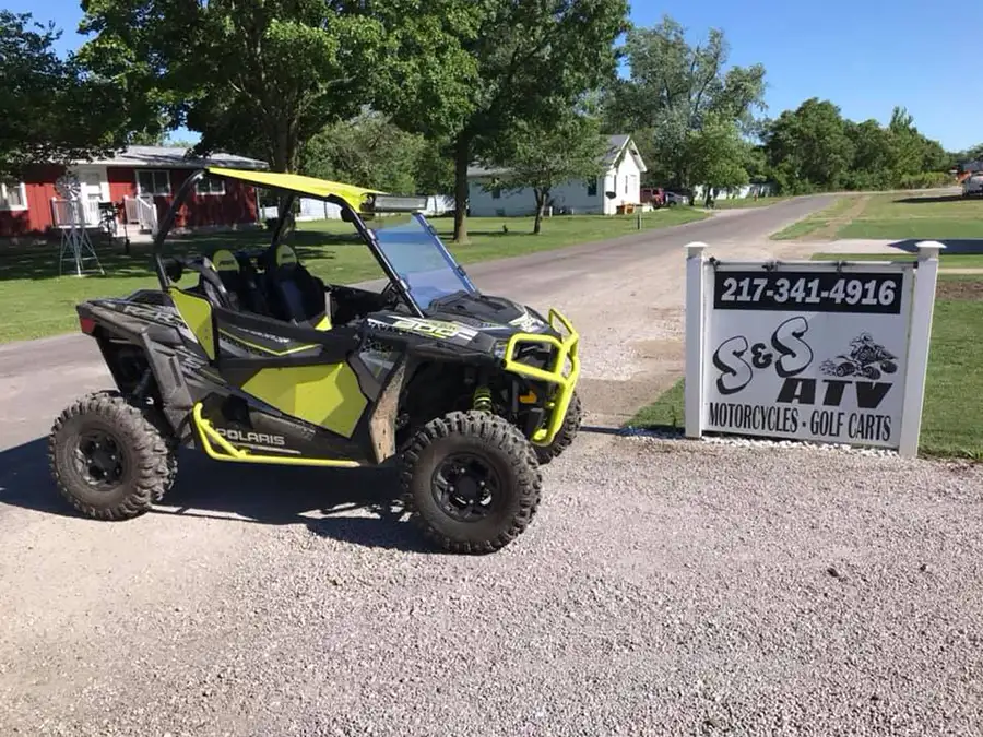 UTV with black and green accents, POLARIS parked in front of shop sign - Carlinville, IL